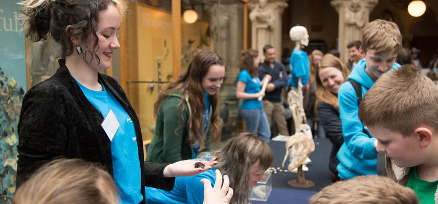 Museum staff with children looking at specimens on a table in the Museum